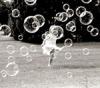 girl jumping and playing with bubbles